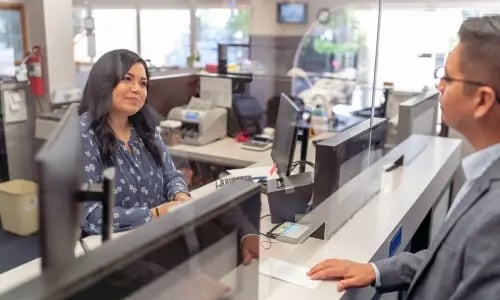 Cajero de banco ayudando a hombre en ventanilla copia