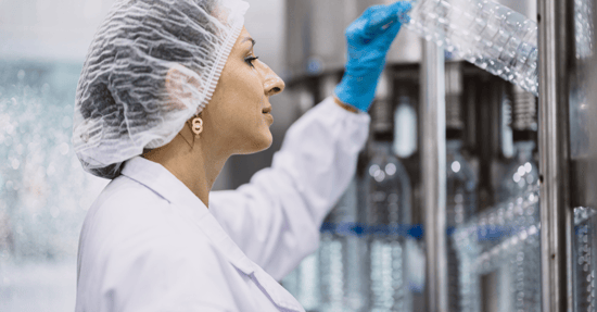 Mujer con redecilla en el pelo y bata de laboratorio examinando plástico 