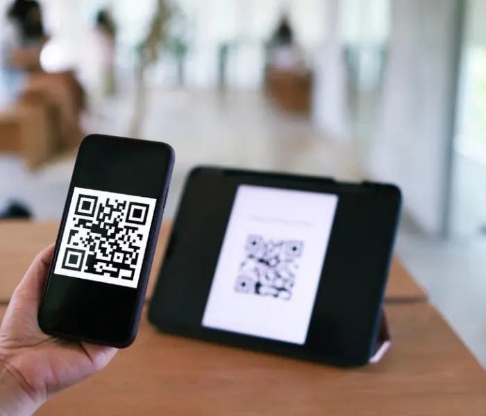 Persona escaneando código QR en tableta con iPhone 