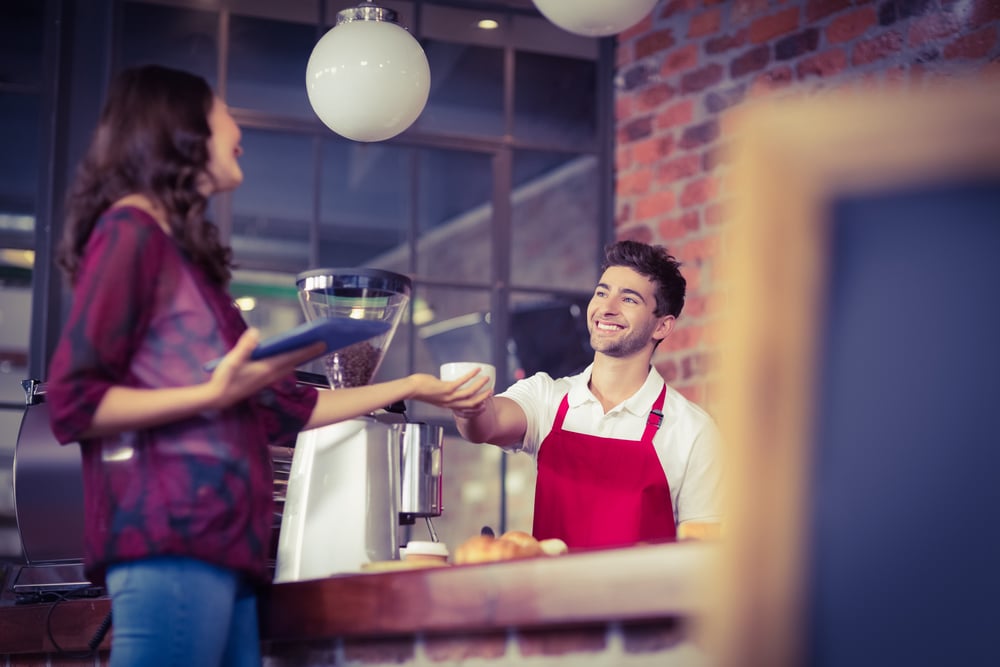 Camarero sonriente atendiendo a un cliente en la cafetería-1