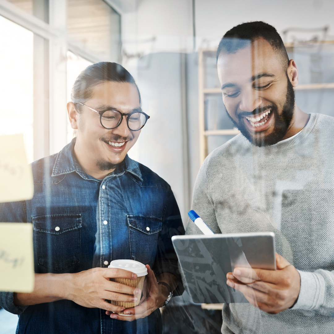 Dos compañeros de trabajo sonriendo y tomando notas en el iPad