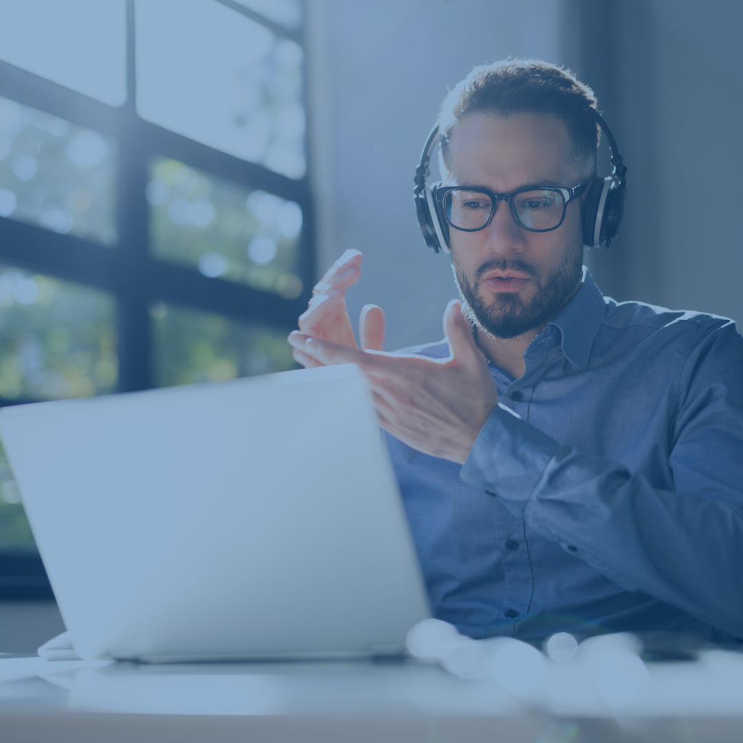 Hombre con auriculares aplaudiendo mientras ve un webinar en un portátil