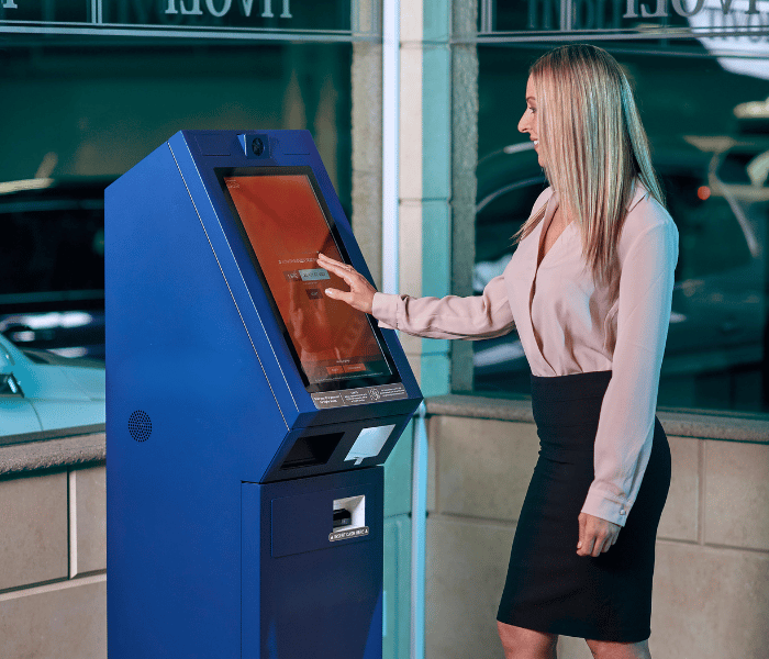 Mujer que utiliza una máquina de autoservicio de última generación en una copia bancaria