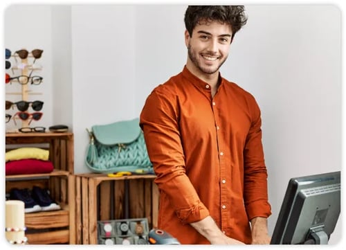 Empleado de comercio con camisa naranja trabajando detrás de un mostrador