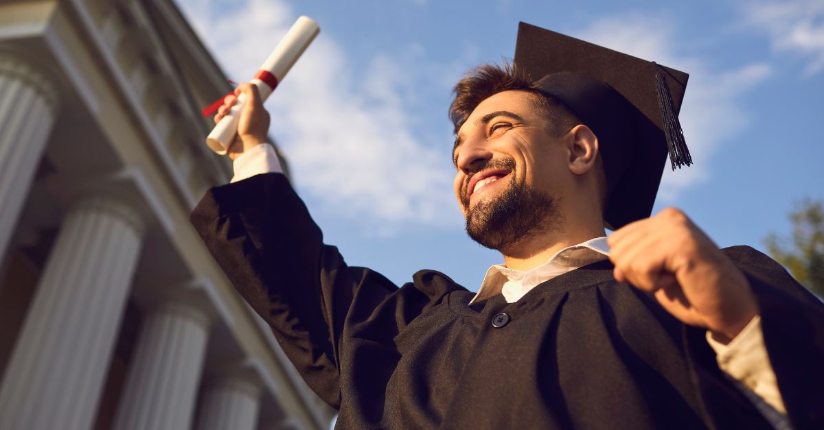 Hombre que se gradúa en la universidad sosteniendo su diploma 