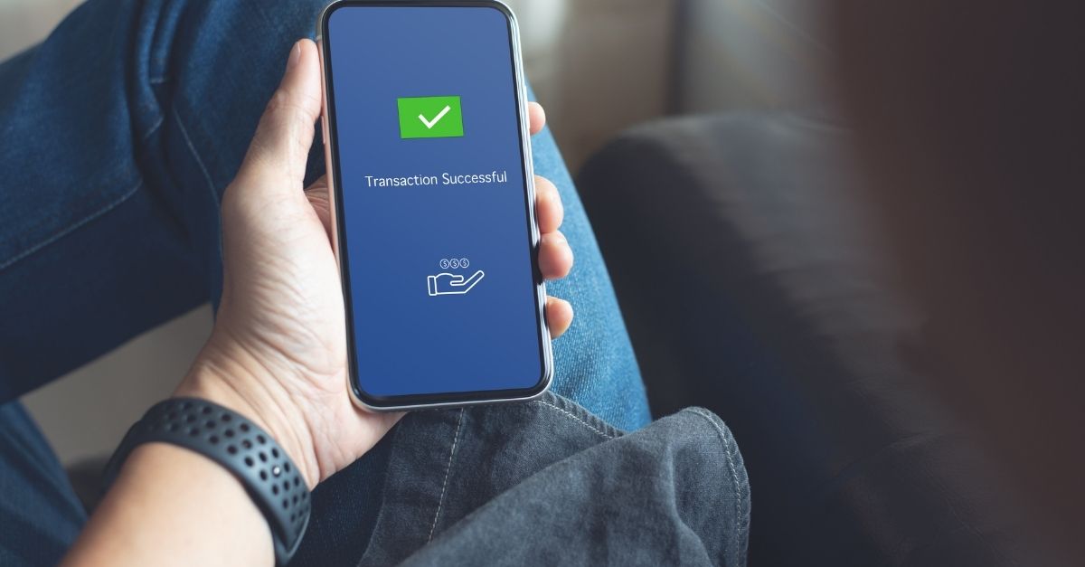 Un hombre mira su transacción realizada con éxito en su smartphone 