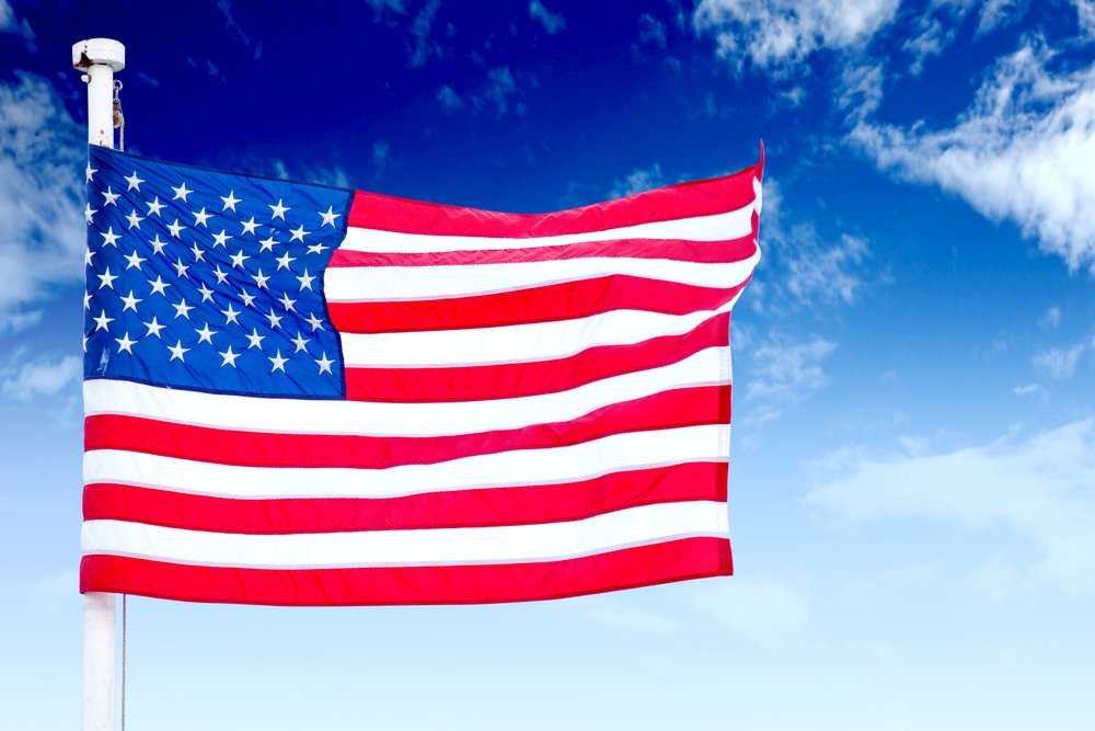 Foto de la la bandera americana ondea en el viento con el cielo azul en el fondo 