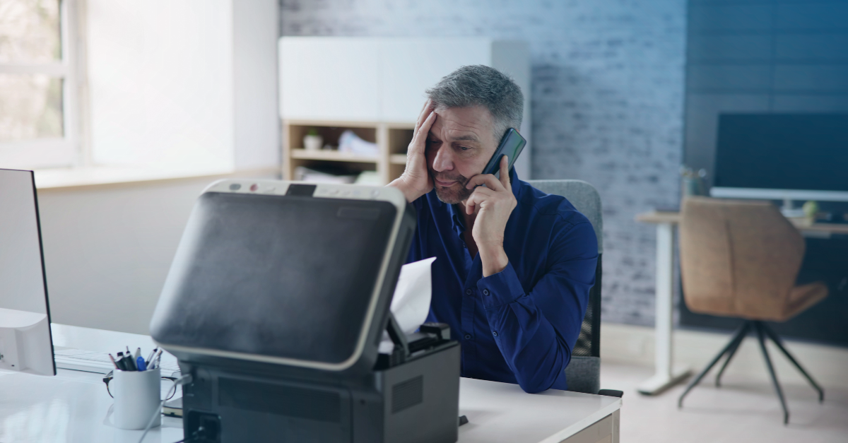 Hombre confuso al teléfono mirando la impresora