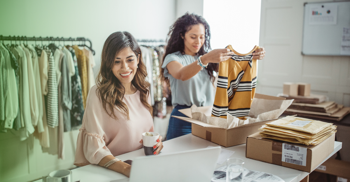 Two women packing clothes into boxes for their small business